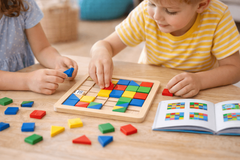 Děti řeší dřevěný logický hlavolam a přemýšlí nad správným řešením